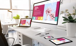 Modern office with multiple devices displaying the same website symbolizing responsive web design. 
